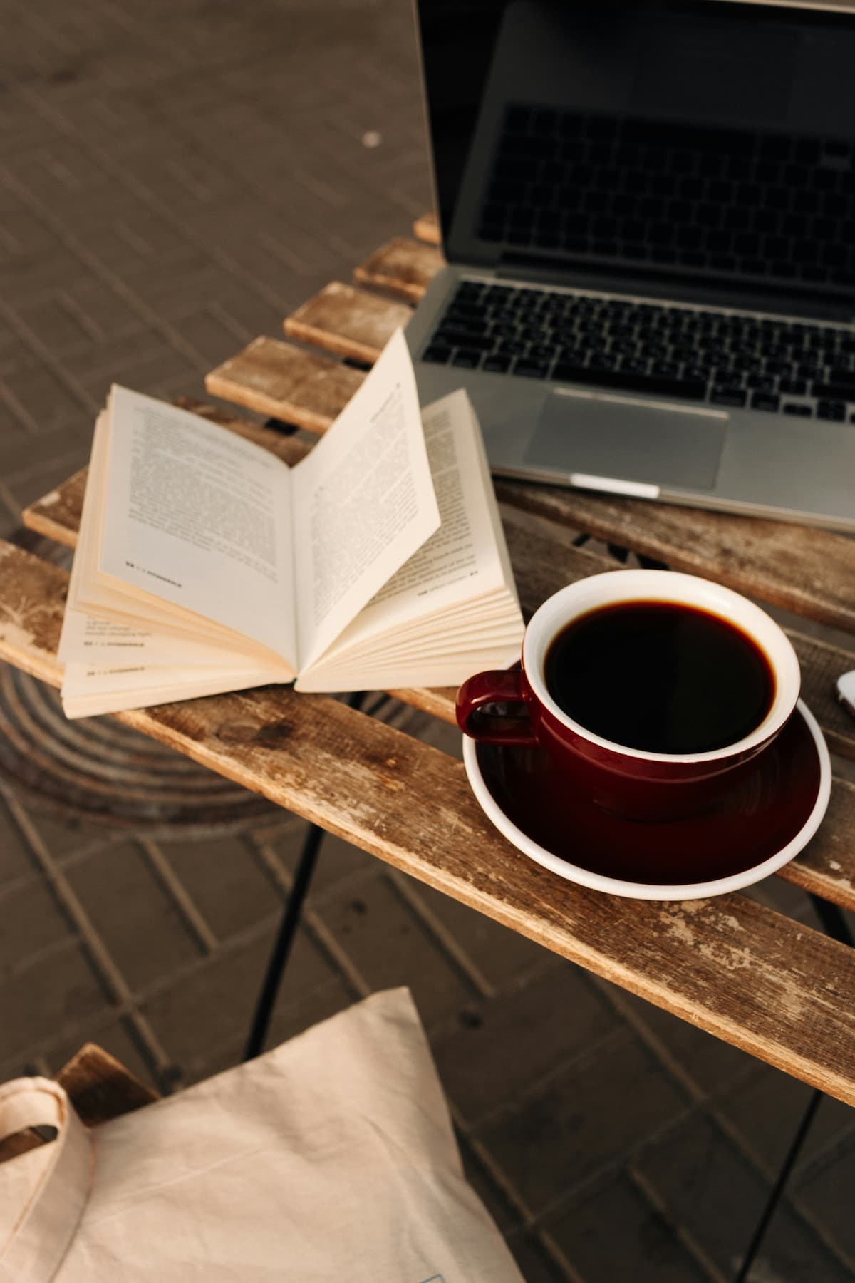 An open book, a cup of coffee and a laptop on a wooden table